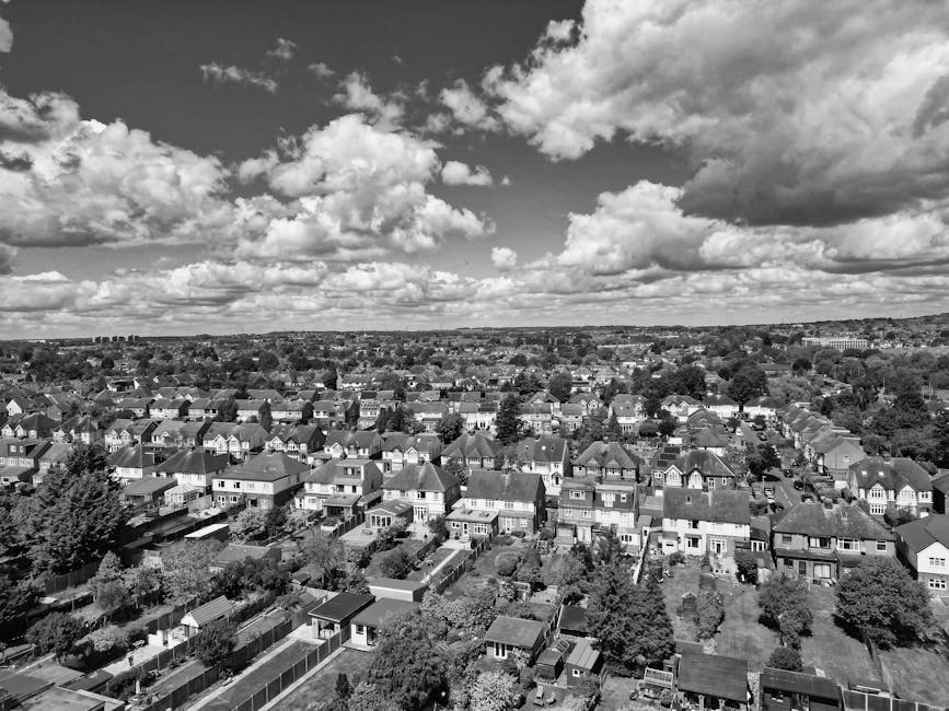 A black-and-white aerial photograph of a residential area on the Becontree Estate in Dagenham, showing numerous closely packed houses with pitched roofs, arranged along a network of streets. In the fo
